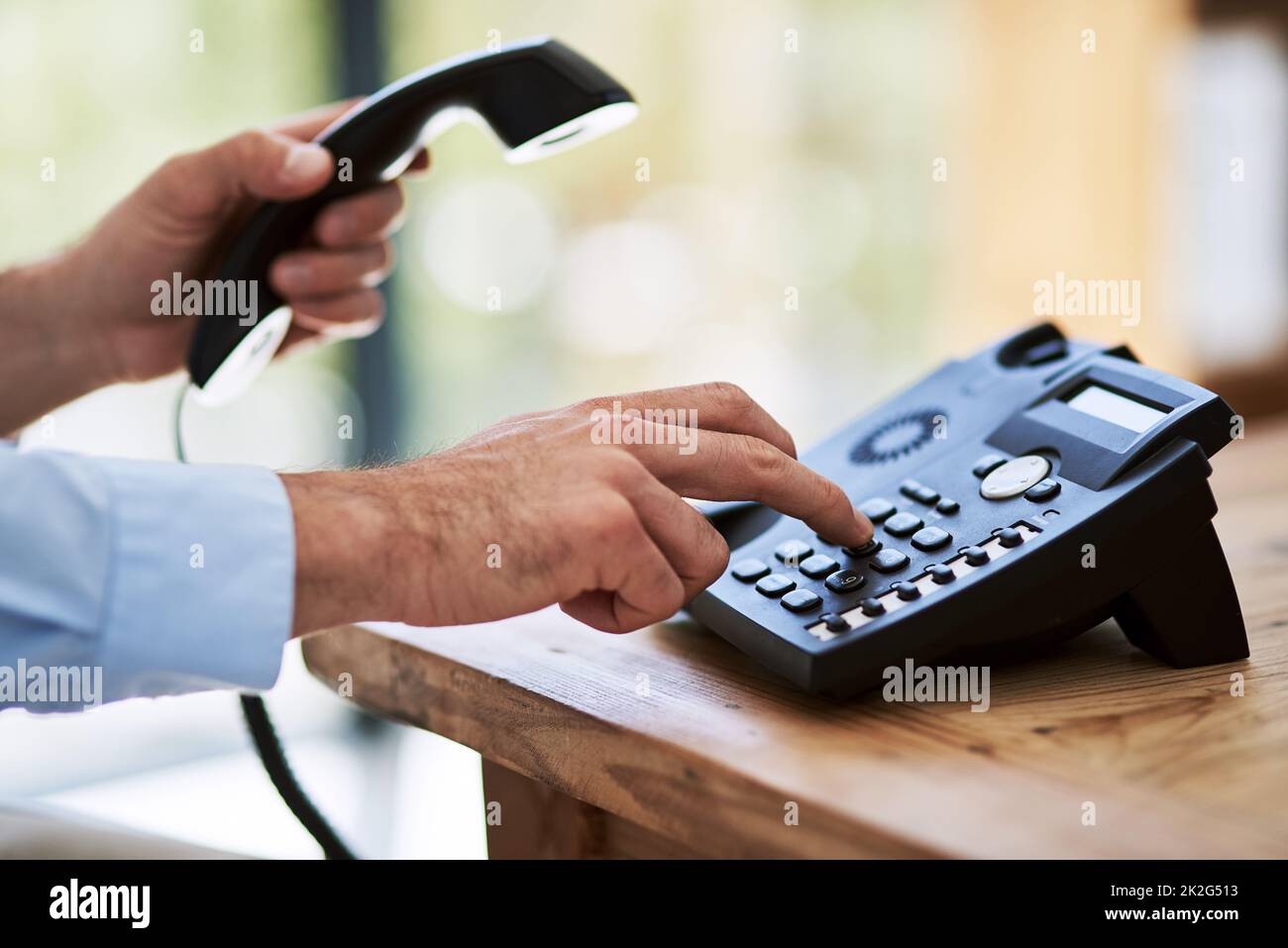 Wählen Sie diese Ziffern. Zugeschnittene Aufnahme eines Mannes, der bei der Arbeit eine Nummer auf einem Telefon anwählt. Stockfoto