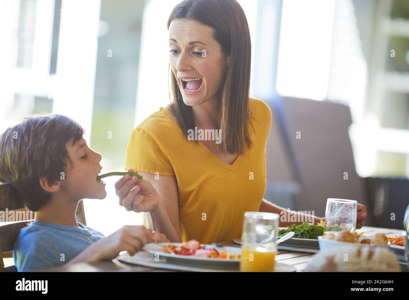 Ich muss das Gemüse essen. Eine kurze Aufnahme einer Mutter und ihres kleinen Sohnes, die zu Hause gemeinsam essen. Stockfoto