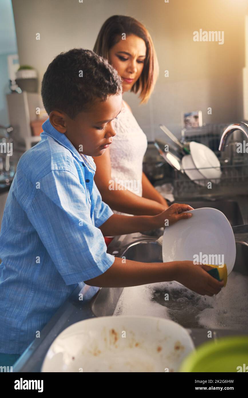 Reinigung bis das Geschirr makellos ist. Aufnahme einer Mutter und eines Sohnes, die zusammen Geschirr waschen. Stockfoto