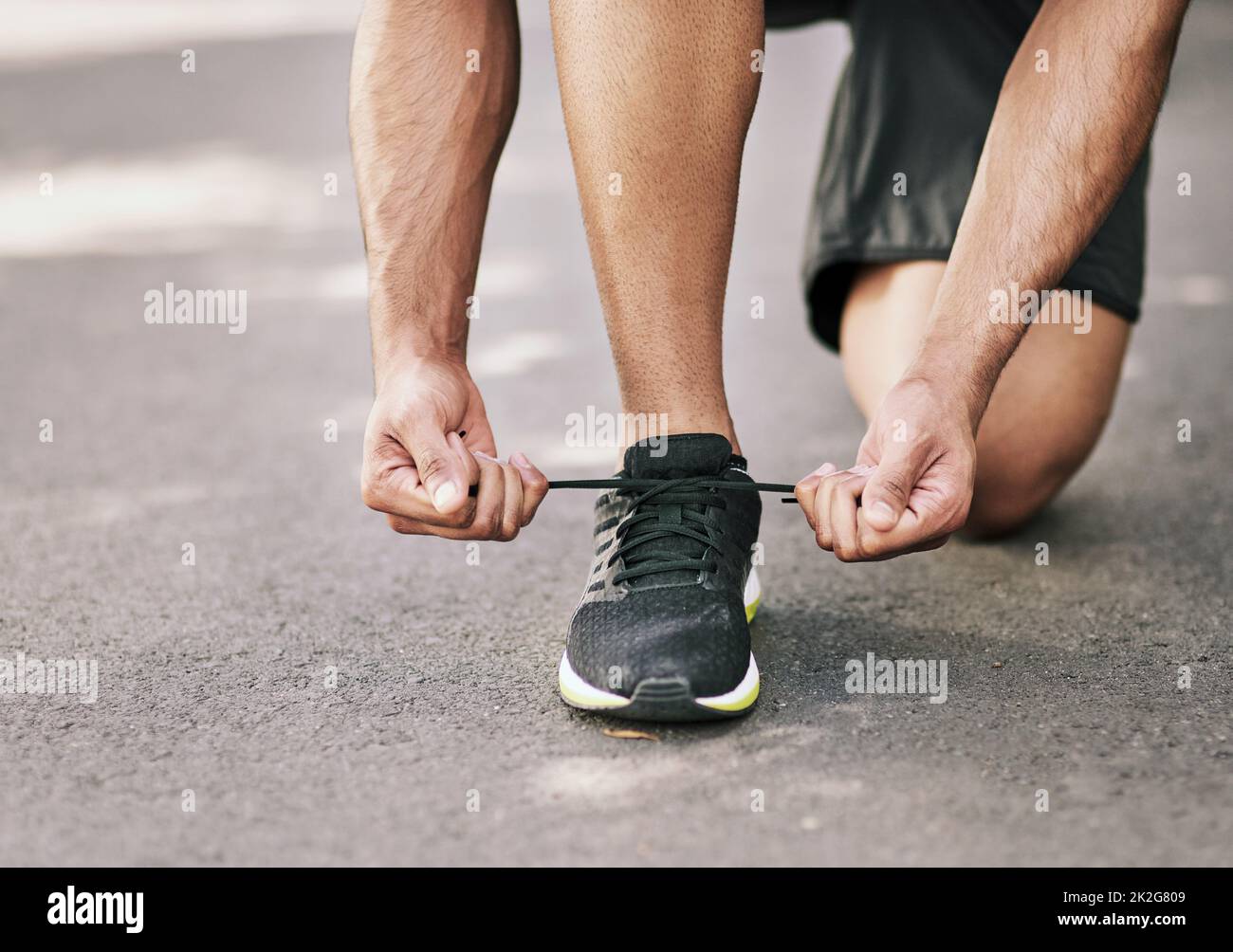 Bereit zum Rennen. Aufnahme eines nicht identifizierbaren jungen Sportlers, der seine Schnürsenkel vor einem Lauf festbindet. Stockfoto
