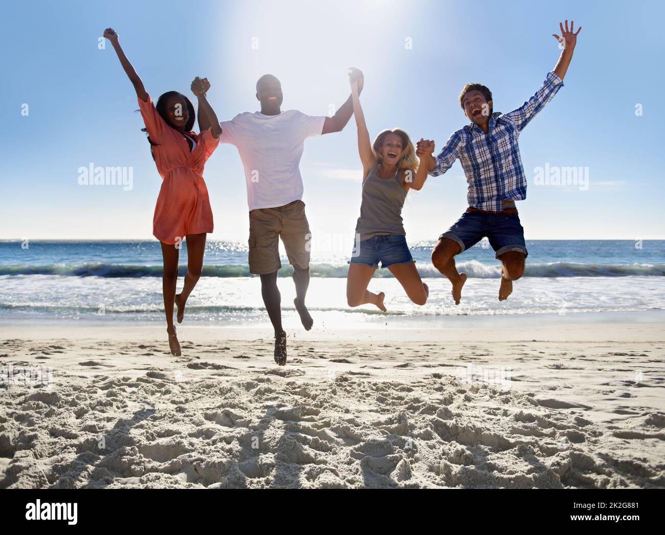 Es ist Sommerzeit. Zwei junge Paare, die am Strand springen und Spaß haben. Stockfoto