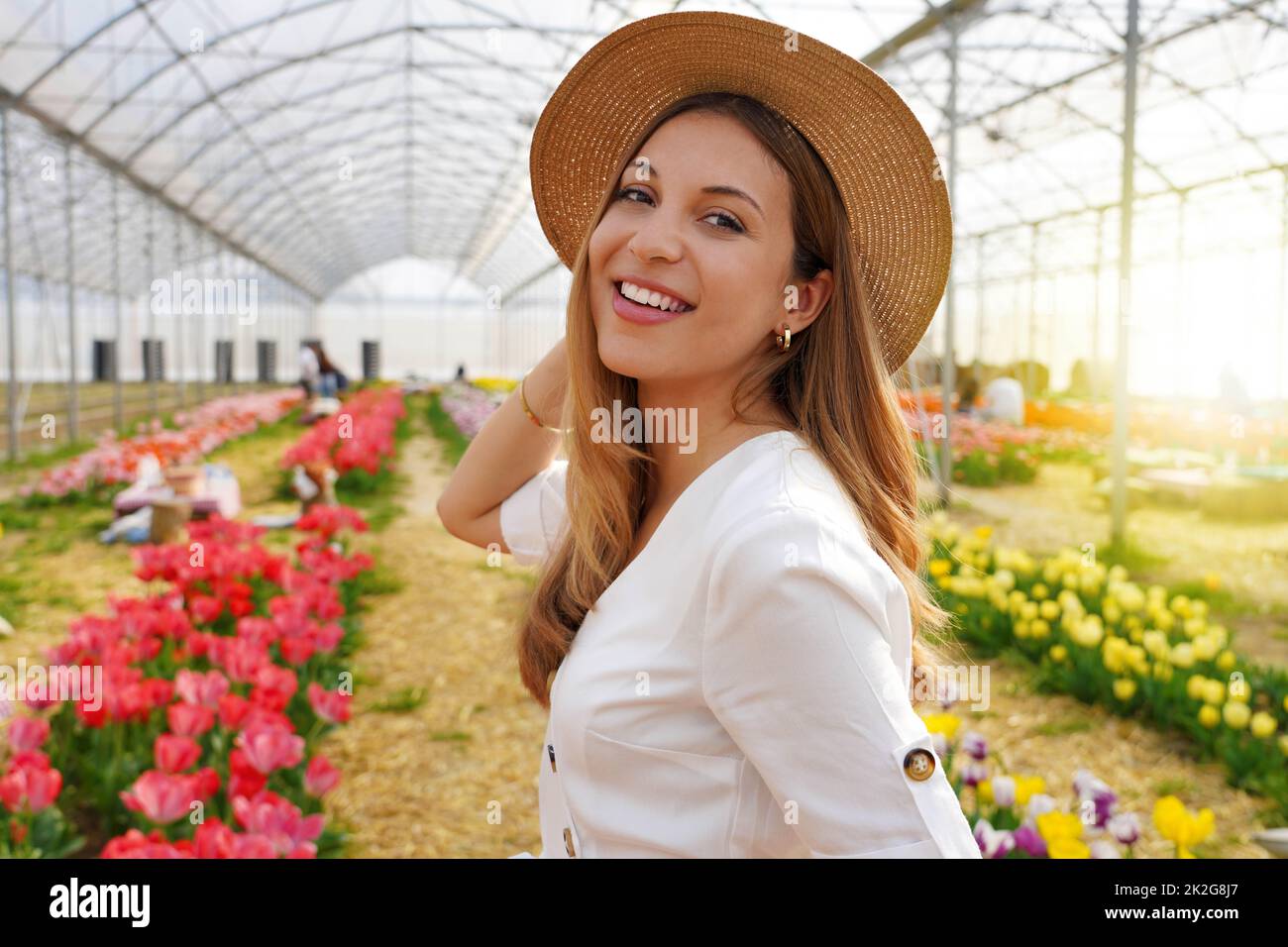 Das Porträt einer lächelnden Frau dreht sich um und schaut auf die Kamera, die zwischen den Tulpen läuft Stockfoto