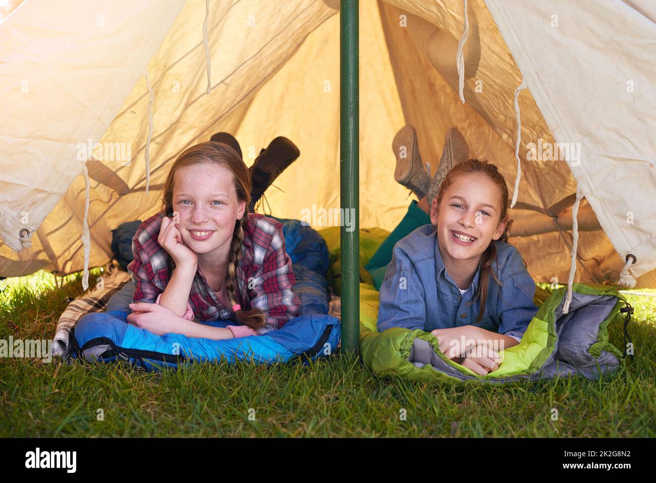 Camping ist das Beste. Zwei junge Mädchen liegen in ihrem Zelt auf ihren Schlafsäcken. Stockfoto
