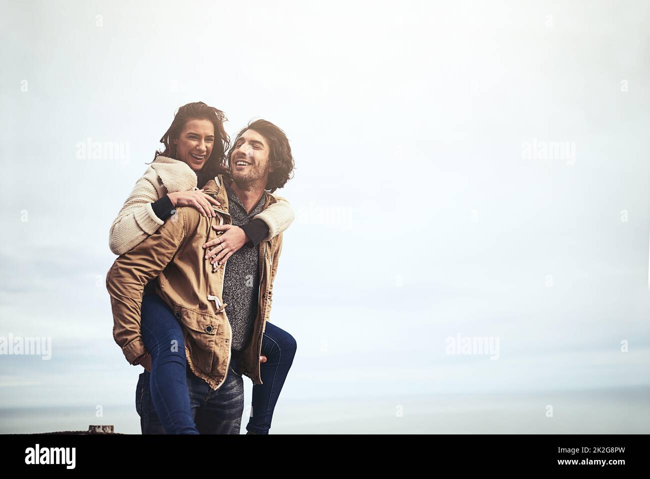 Das Leben ist besser mit Liebe darin. Porträt einer liebevollen jungen Frau, die einen Huckepack auf ihrem Freund macht, während sie draußen in die Kamera schaut. Stockfoto