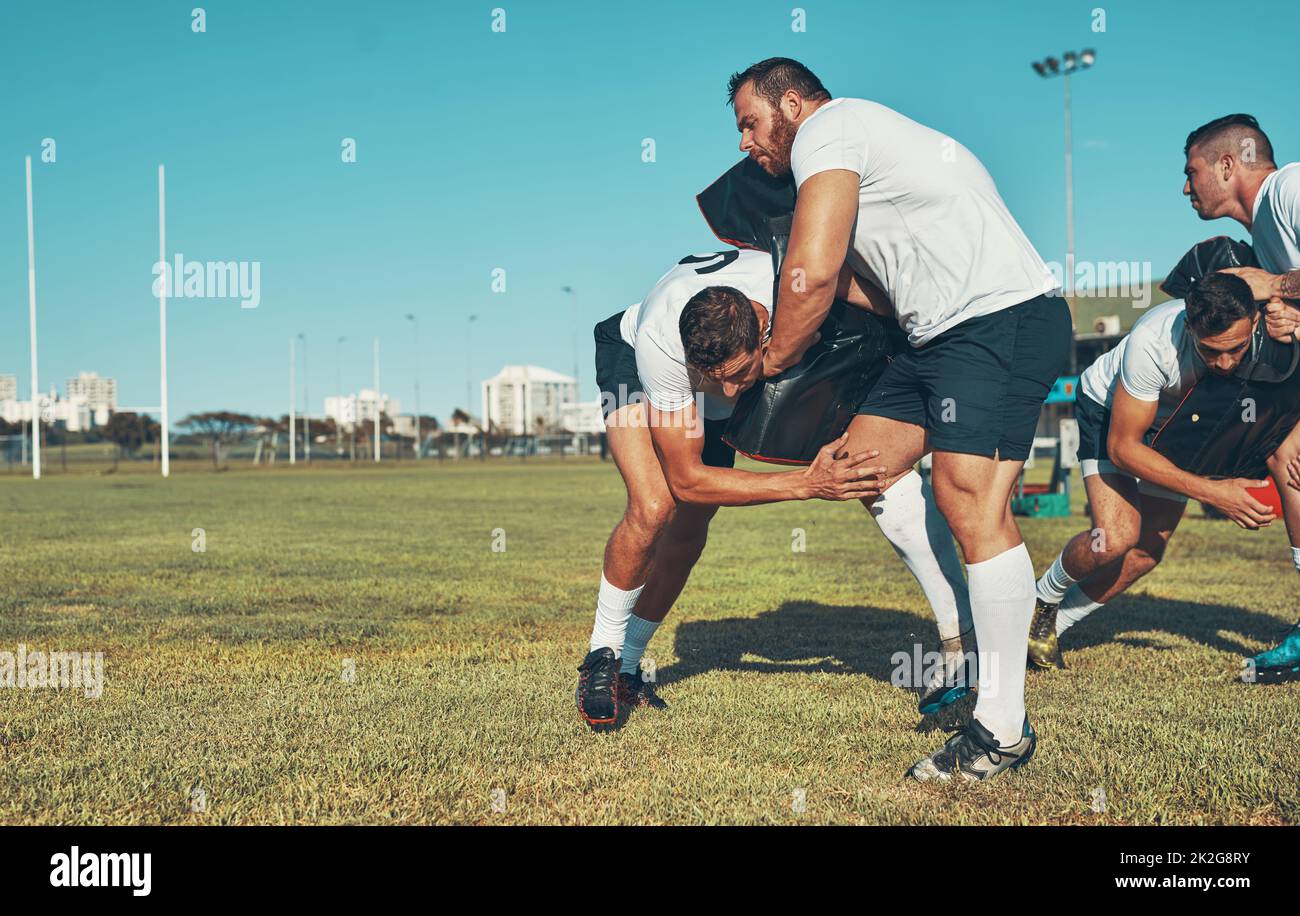 Die Grundlagen des sicheren und effektiven Tacklings zu meistern. Aufnahme von Rugby-Spielern, die auf dem Spielfeld mit Tackle Bags trainieren. Stockfoto