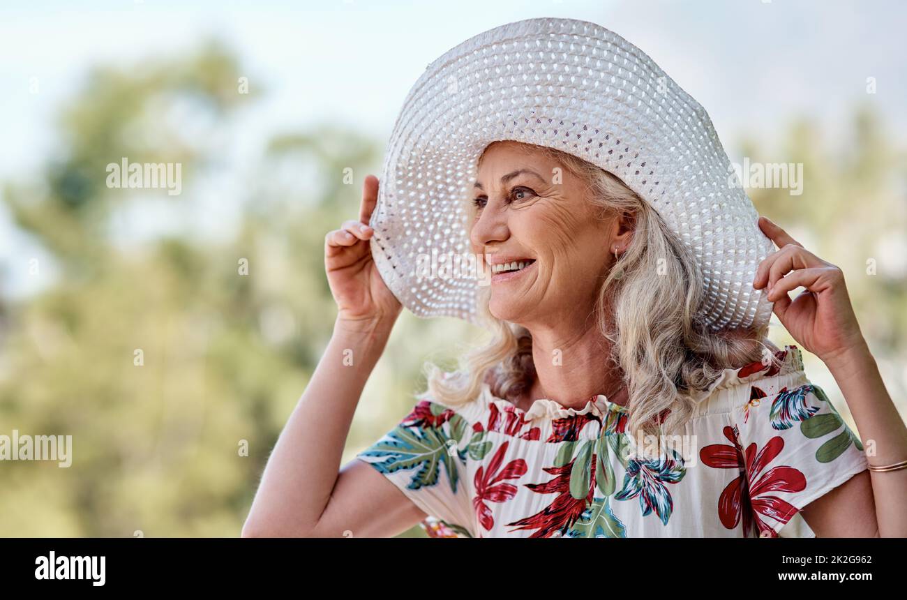 Wenn man älter wird, genießt man den Sommer mehr. Kurze Aufnahme einer attraktiven Seniorin, die an einem Sommertag im Freien lächelt. Stockfoto