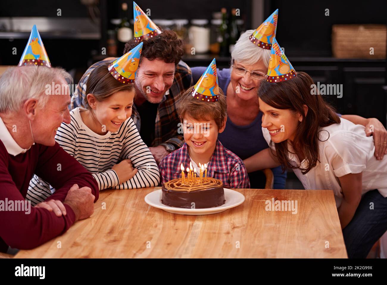 Machen Sie einen Wunsch, bevor Sie sie ausblasen. Aufnahme eines glücklichen Jungen, der mit seiner Familie Geburtstag feiert. Stockfoto