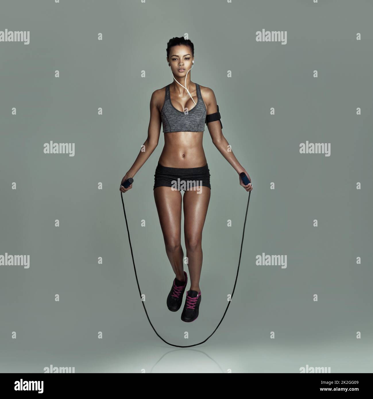 Überspringen Sie nie ein Workout. Studioaufnahme einer jungen Frau, die vor grauem Hintergrund springt. Stockfoto
