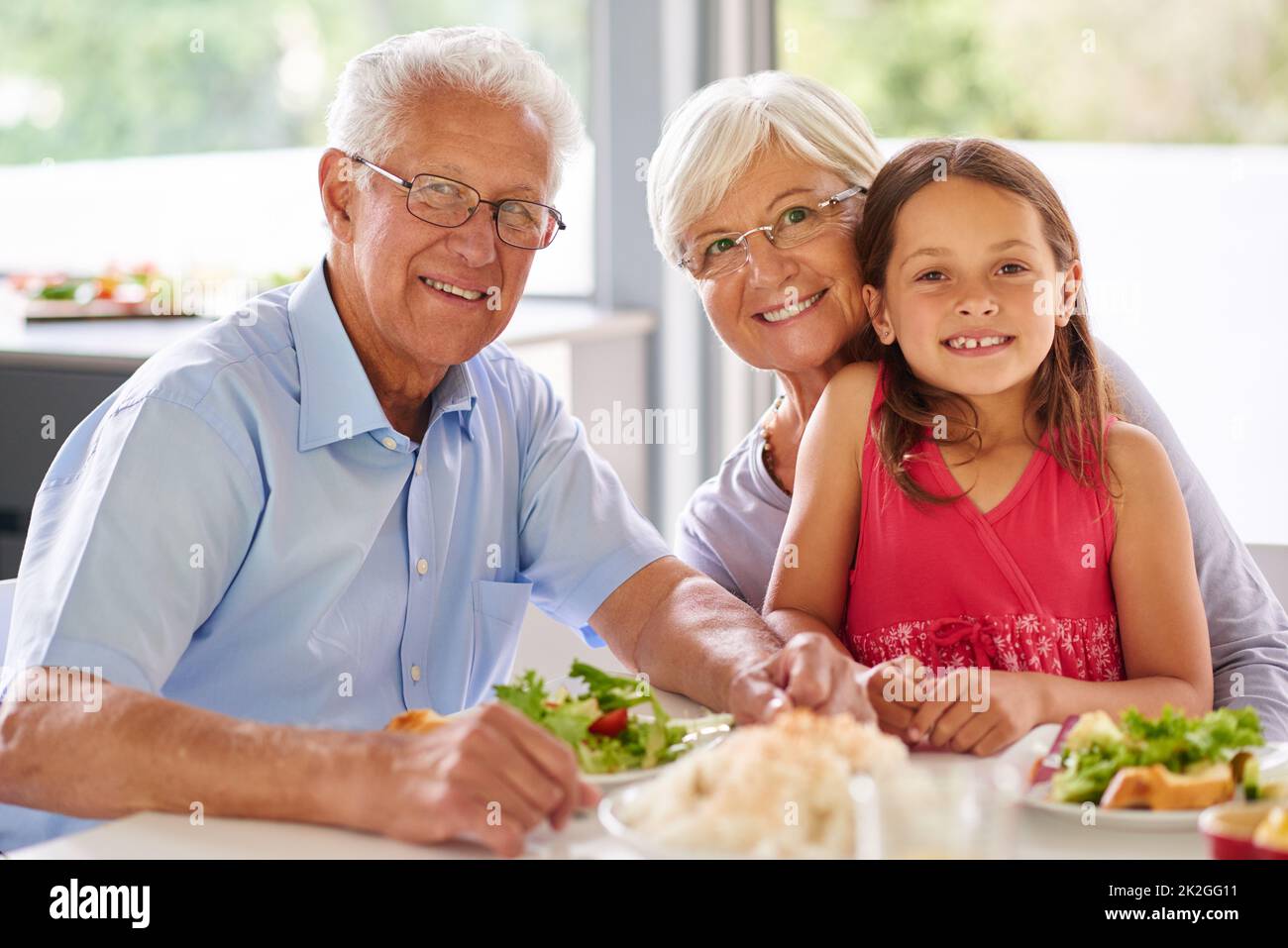 Gut essen hat sie spritulich gehalten. Porträt eines kleinen Mädchens, das mit ihren Großeltern zu Mittag gegessen hat. Stockfoto