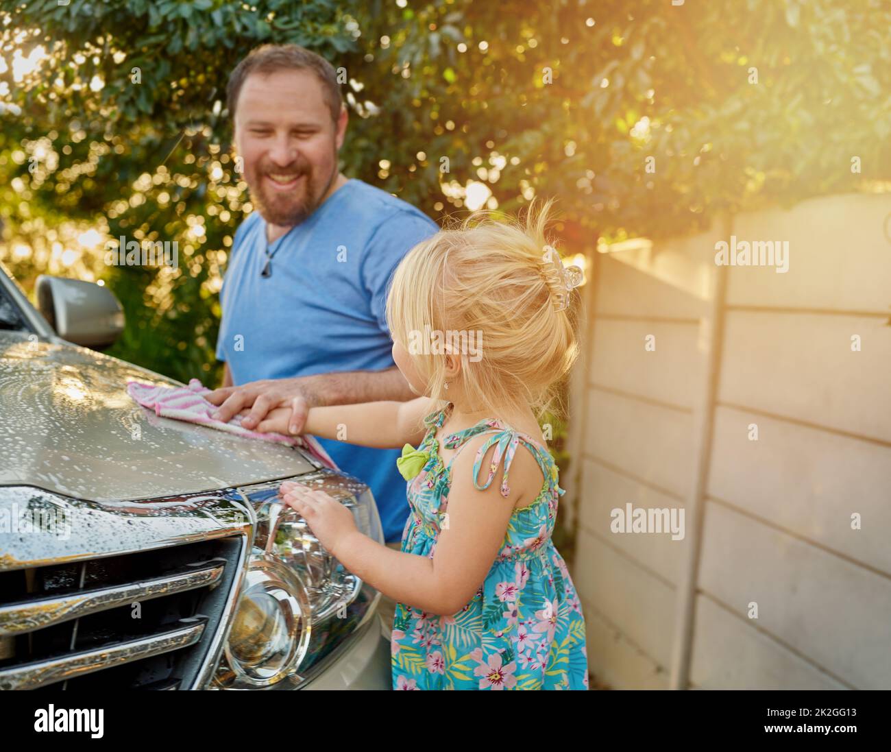 Die gemeinsame Arbeit ist eine großartige Erfahrung im miteinander. Eine kleine Aufnahme eines Vaters und einer Tochter, die zusammen ein Auto waschen. Stockfoto