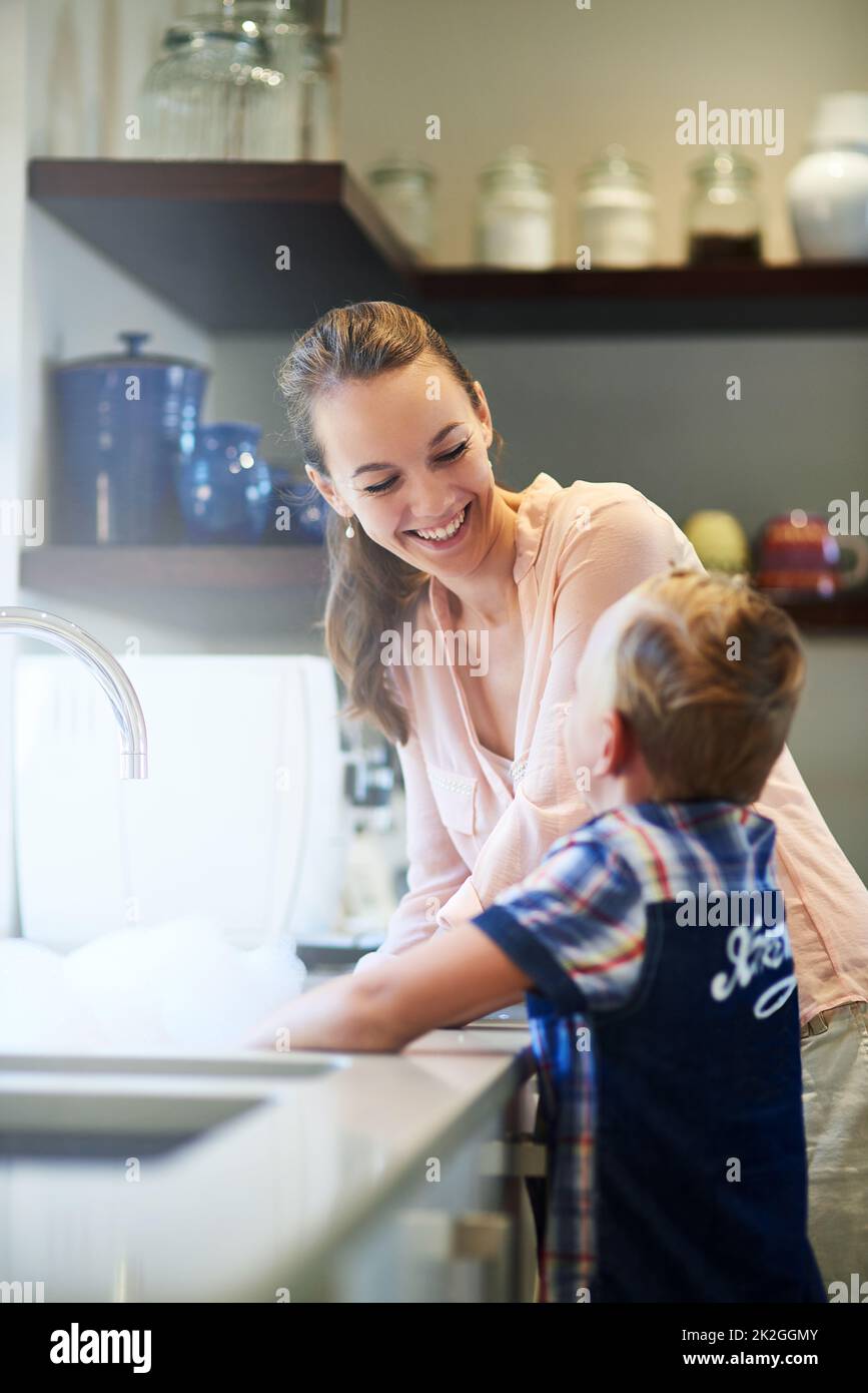 Kleben zu Hause. Aufnahme einer Mutter und eines Sohnes, die zusammen Geschirr waschen. Stockfoto