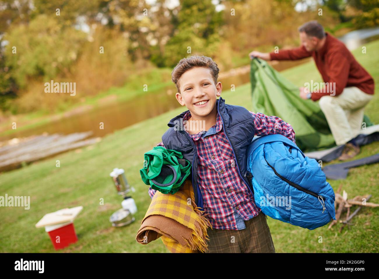 Alles außer dem Spülbecken in der Küche. Porträt eines Jungen, der Campingausrüstung mit seinem Vater im Hintergrund hält. Stockfoto