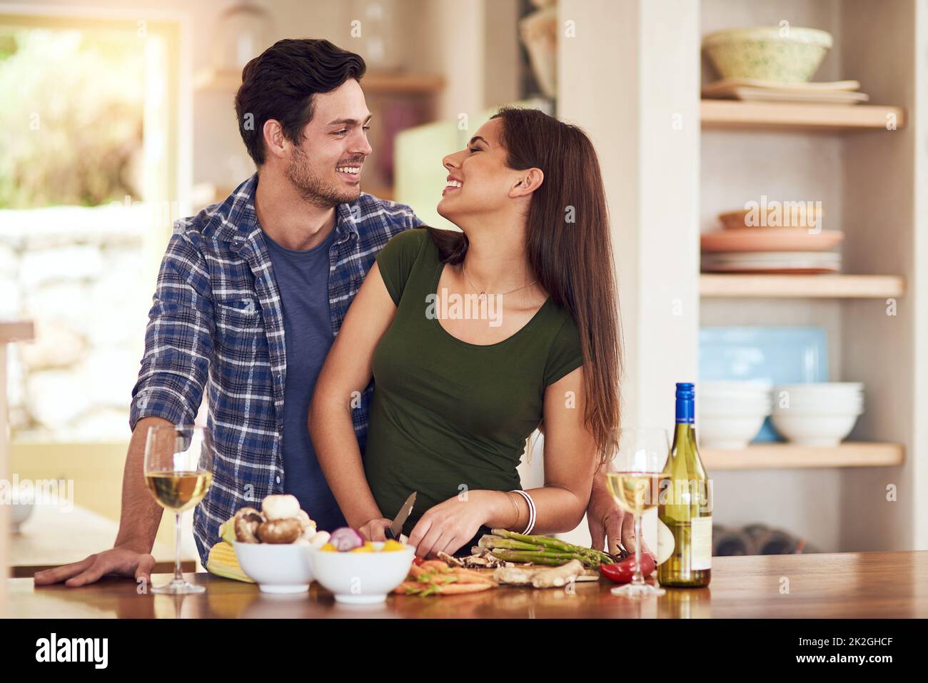 Darf ich den Koch küssen? Aufnahme eines jungen Paares, das gemeinsam in seiner Küche zu Hause das Abendessen zubereitet. Stockfoto