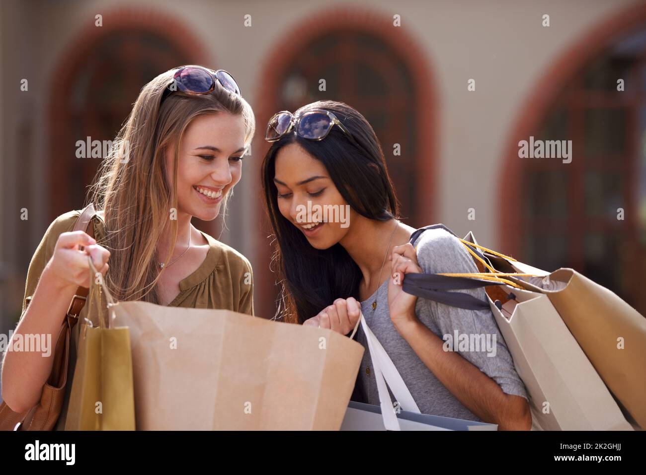 Zeigen und erzählen. Zwei junge Damen schauen sich ihre Einkäufe des Tages an. Stockfoto
