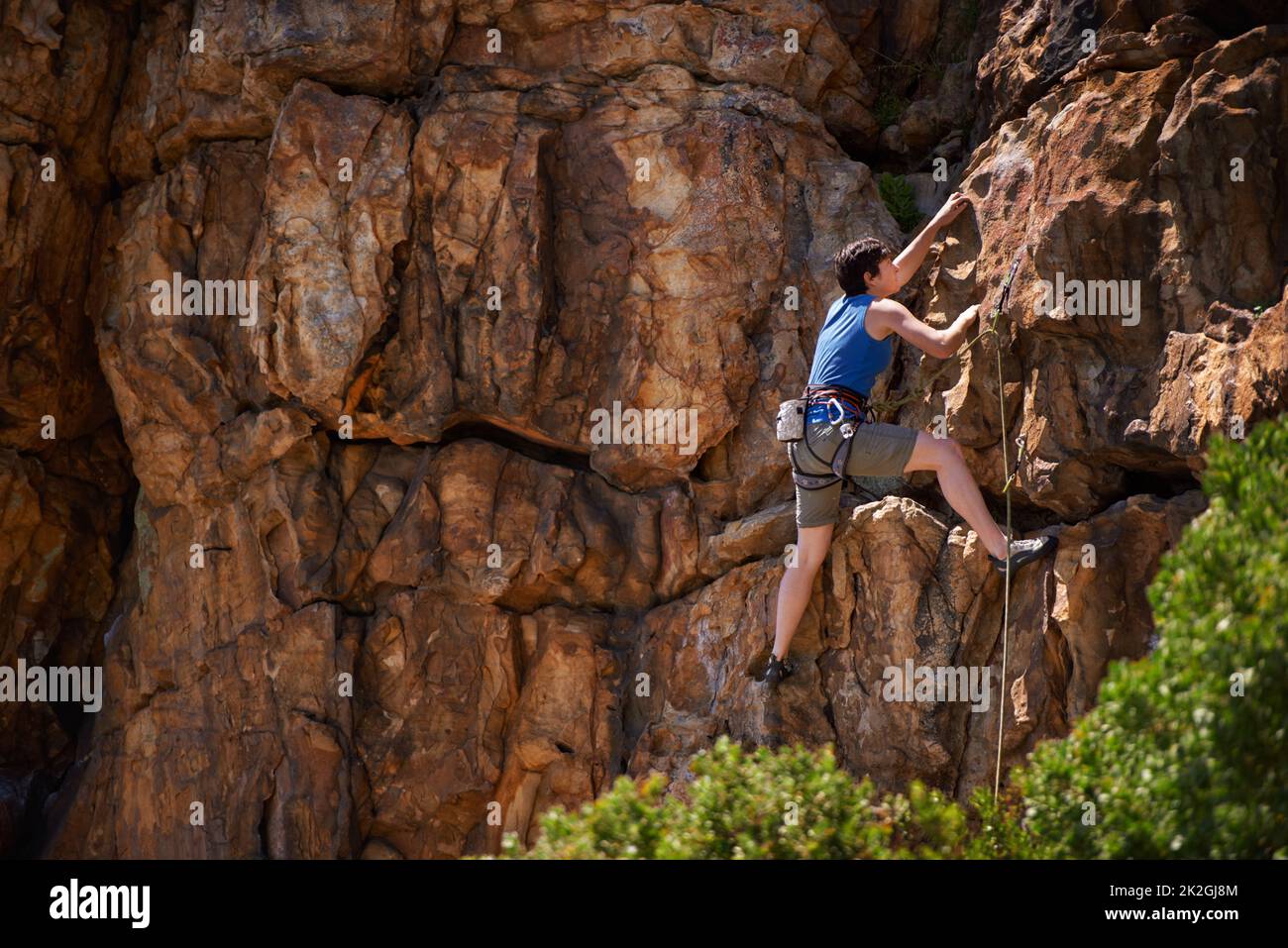 Fest anhängen. Eine breite Aufnahme einer jungen Frau beim Klettern. Stockfoto