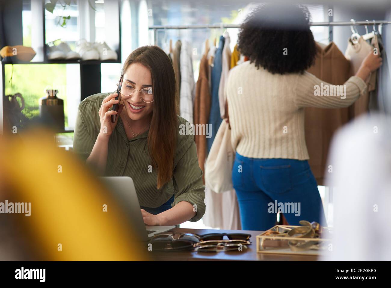 Ihre Bestellung ist verpackt und auf dem fröhlichen Weg. Aufnahme einer Frau, die während der Arbeit in einem Bekleidungsgeschäft auf ihrem Handy sprach. Stockfoto