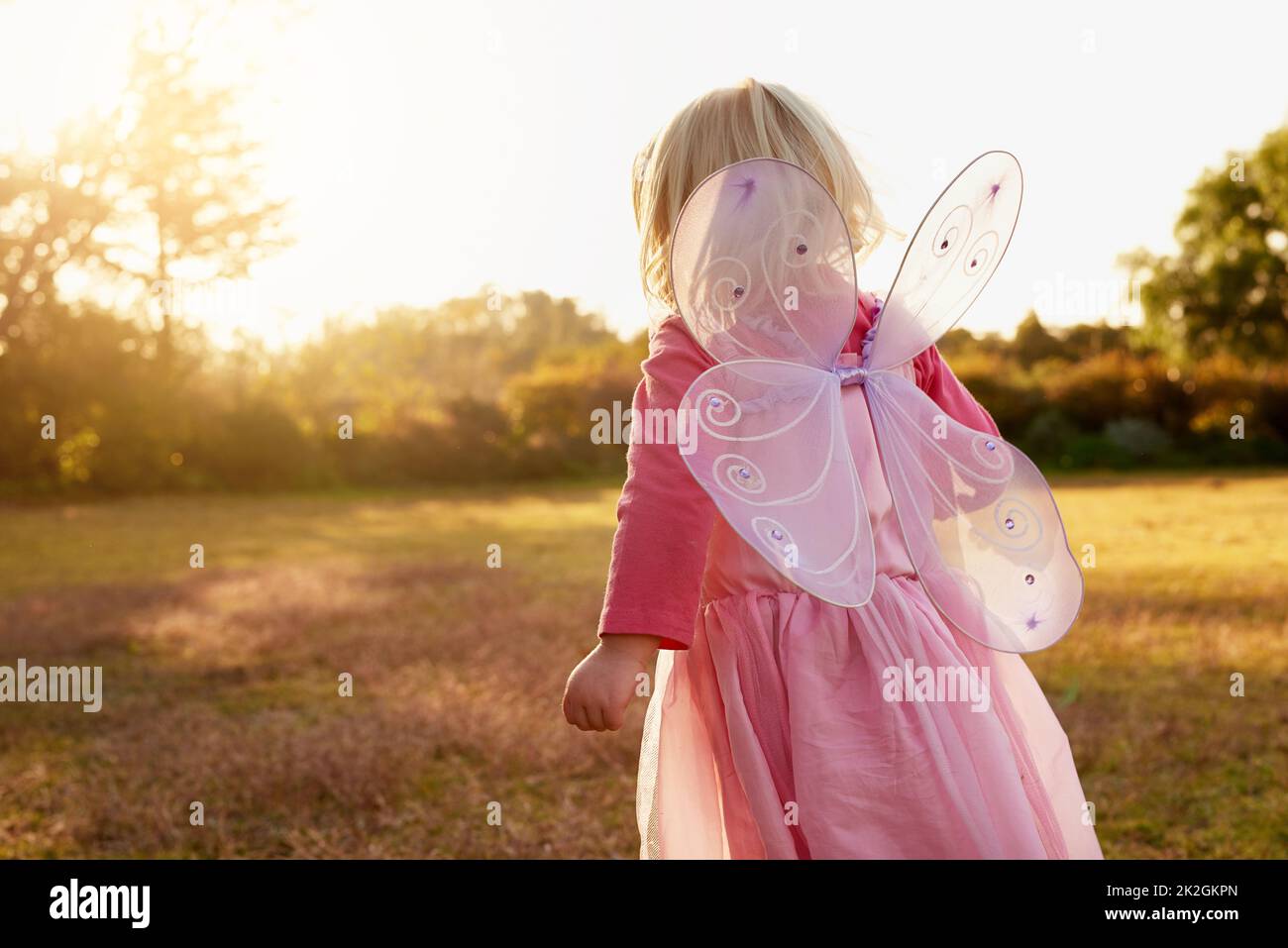 Kinder erkunden die Welt durch die Kraft ihrer Vorstellungskraft. Rückansicht eines kleinen Mädchens, das als Fee verkleidet ist und den Tag draußen genießt. Stockfoto