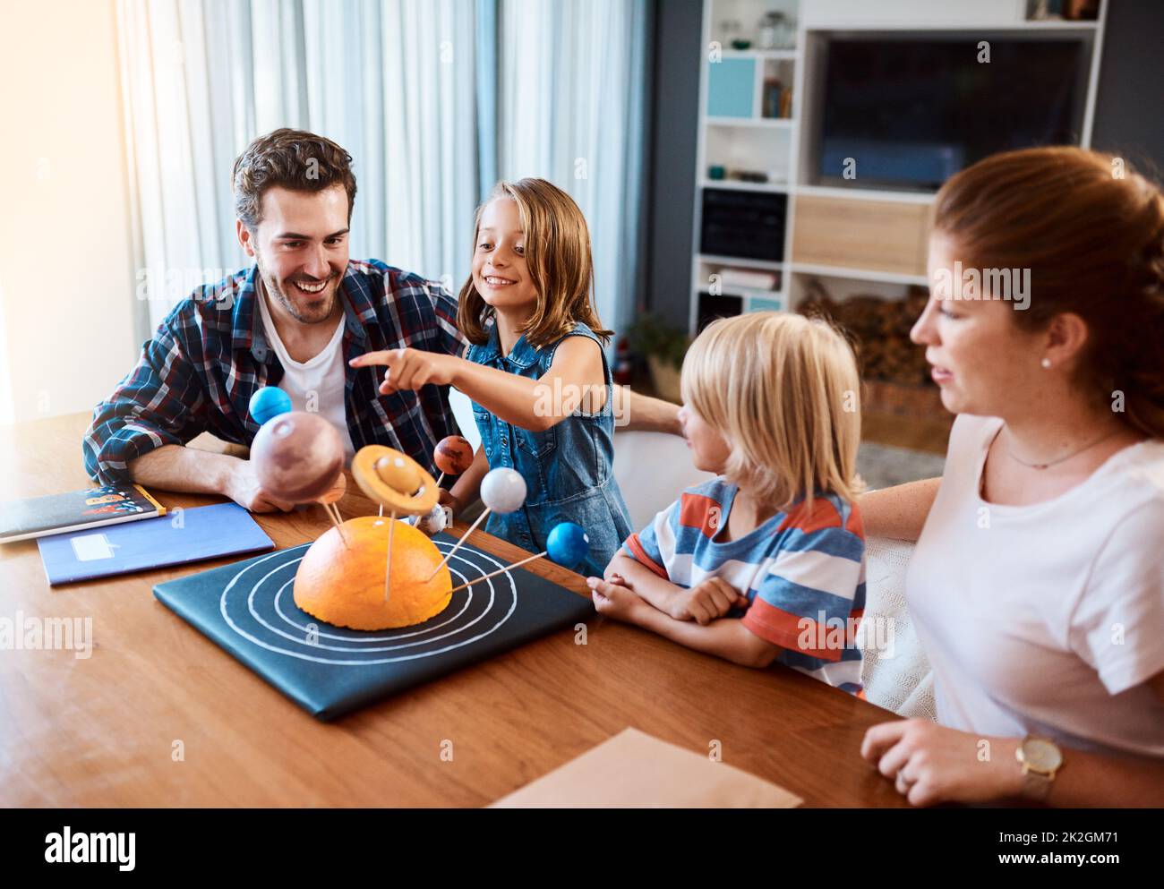 Waren zusammen durch das Universum unterwegs. Aufnahme einer schönen jungen Familie, die zu Hause an einem wissenschaftlichen Projekt arbeitet. Stockfoto