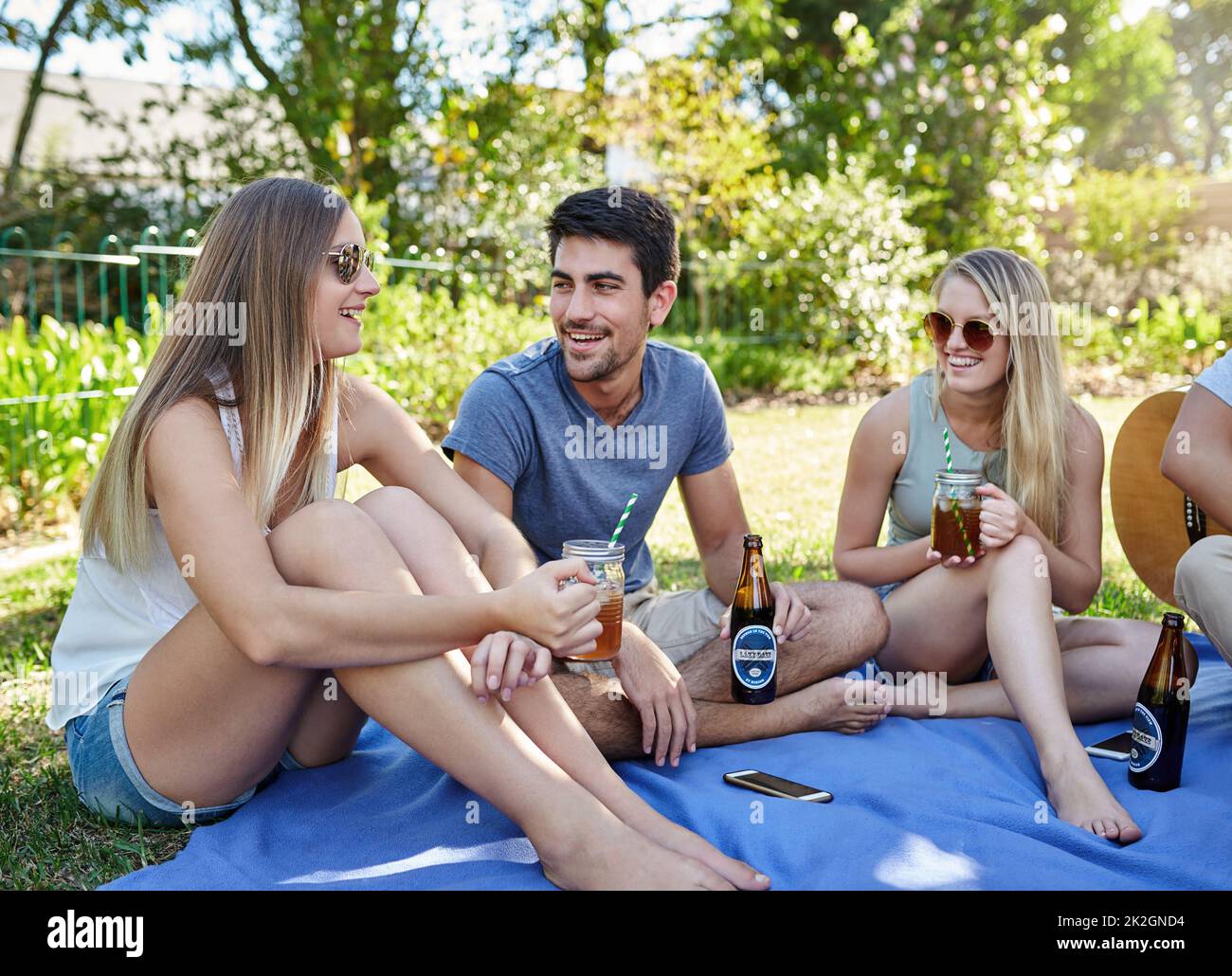 Mit Freunden chillen. Eine kleine Aufnahme einer jungen Gruppe von Freunden, die in der Sommersonne ein paar Drinks genießen. Stockfoto