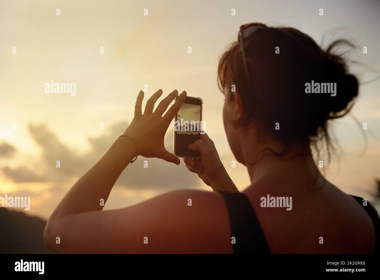 Ich kann es kaum erwarten, diese Ansicht zu teilen. Aufnahme einer jungen Frau, die im Urlaub mit ihrem Handy einen tropischen Ausblick fotografiert. Stockfoto