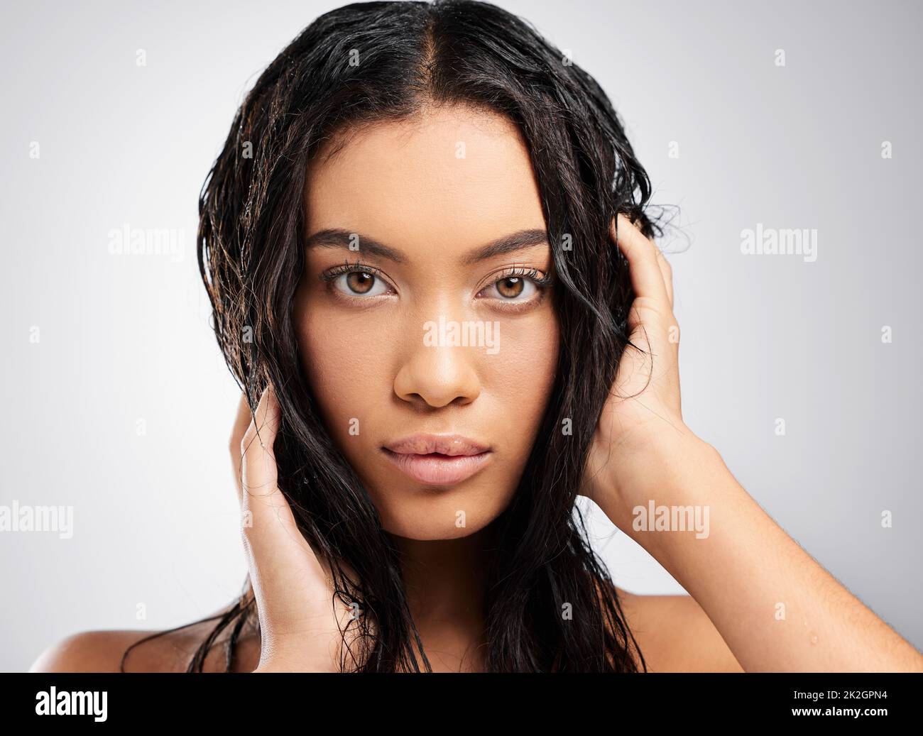 Mühelos schön. Beschnittenes Porträt einer attraktiven jungen Frau, die im Studio vor grauem Hintergrund posiert. Stockfoto