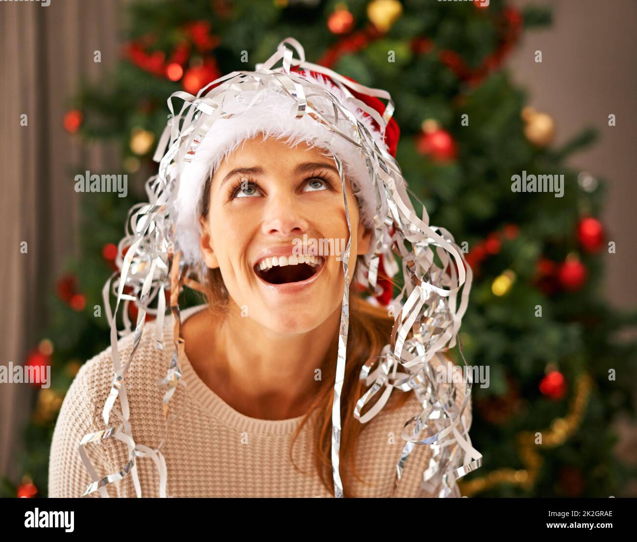 Es schneit. Aufnahme einer schönen jungen Frau, die einen verspielten Moment mit Weihnachtsdekorationen genießt. Stockfoto