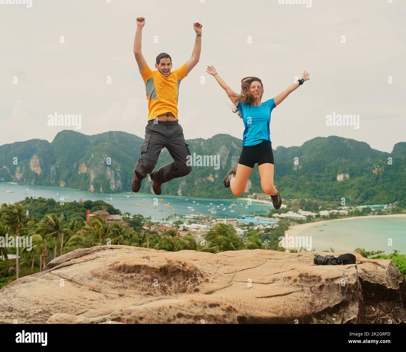 Wir lieben das Inselleben. Aufnahme eines glücklichen jungen Paares, das vor einer Insellandschaft springt. Stockfoto