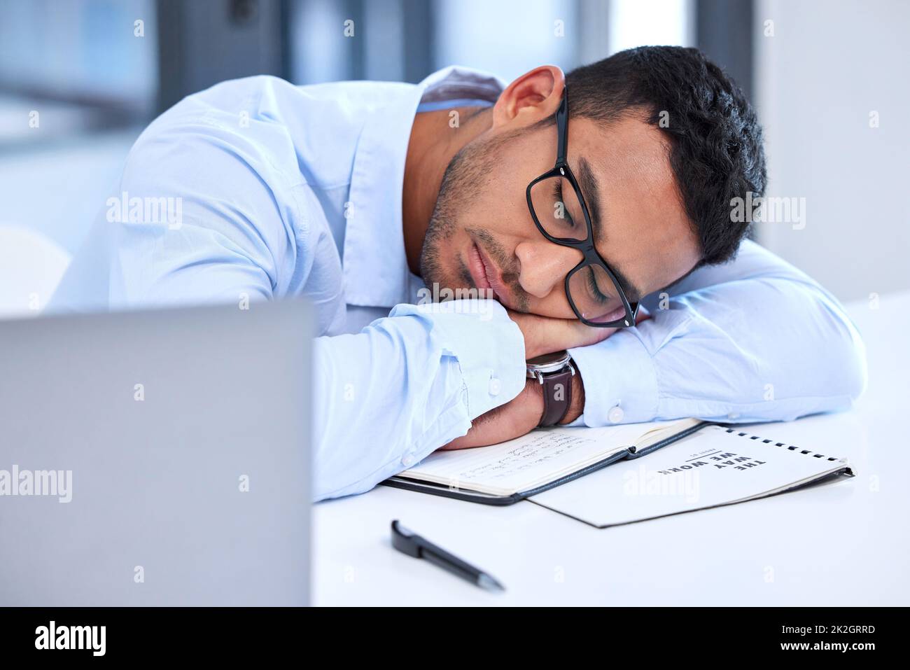 Ich bin seit 6am aktiv. Aufnahme eines jungen Geschäftsmannes, der bei der Arbeit ein Nickerchen macht. Stockfoto