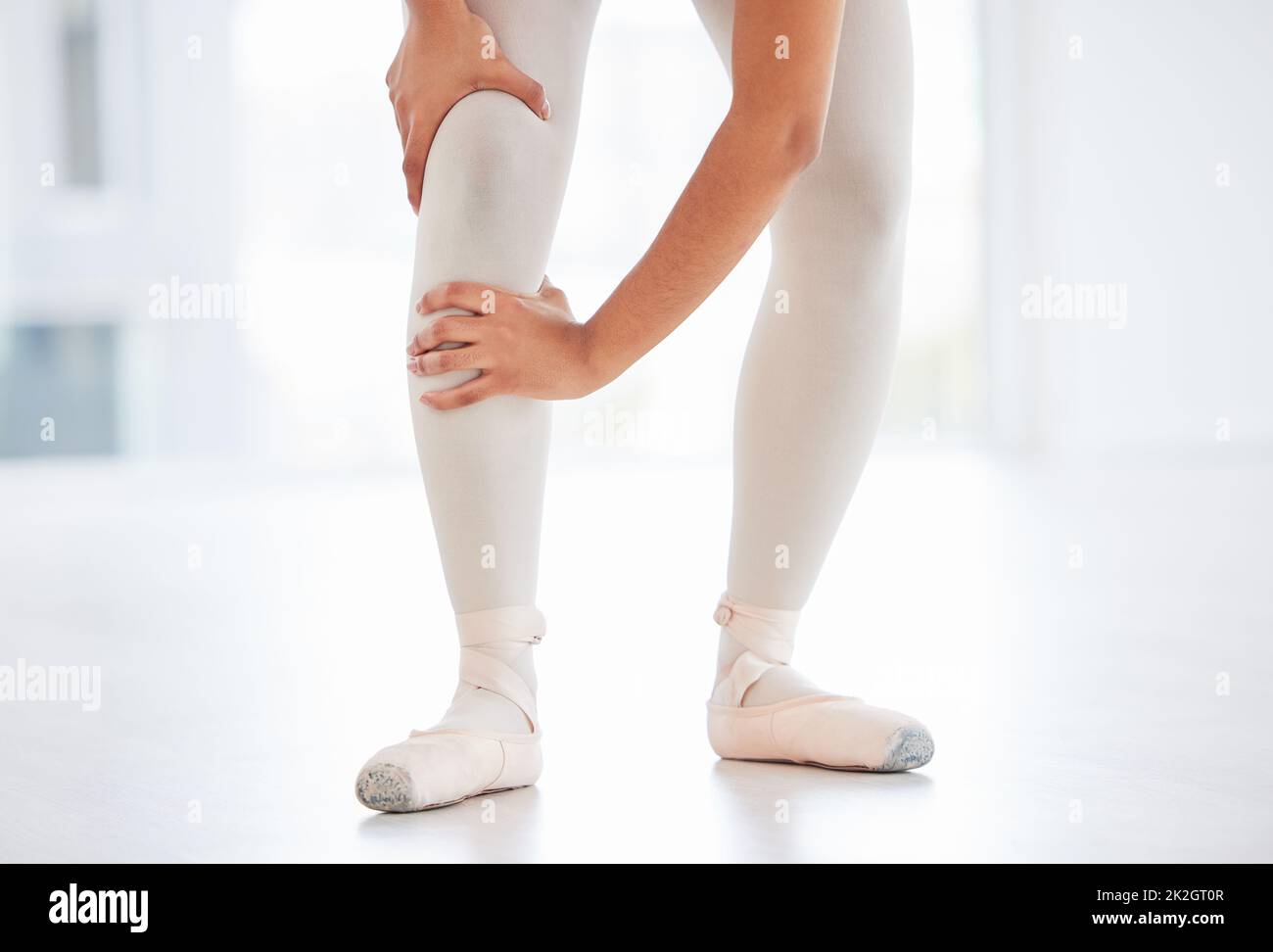 Während des Trainings habe ich mein Knie verletzt. Kurzer Schuss einer Ballerina, die ihr Bein vor Schmerzen hält. Stockfoto