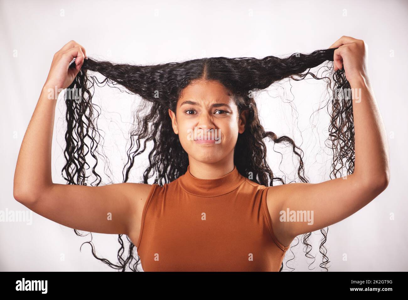 Sollte ich etwas anderes damit machen? Aufnahme einer jungen Frau mit langen braunen Haaren, die im Studio posiert. Stockfoto