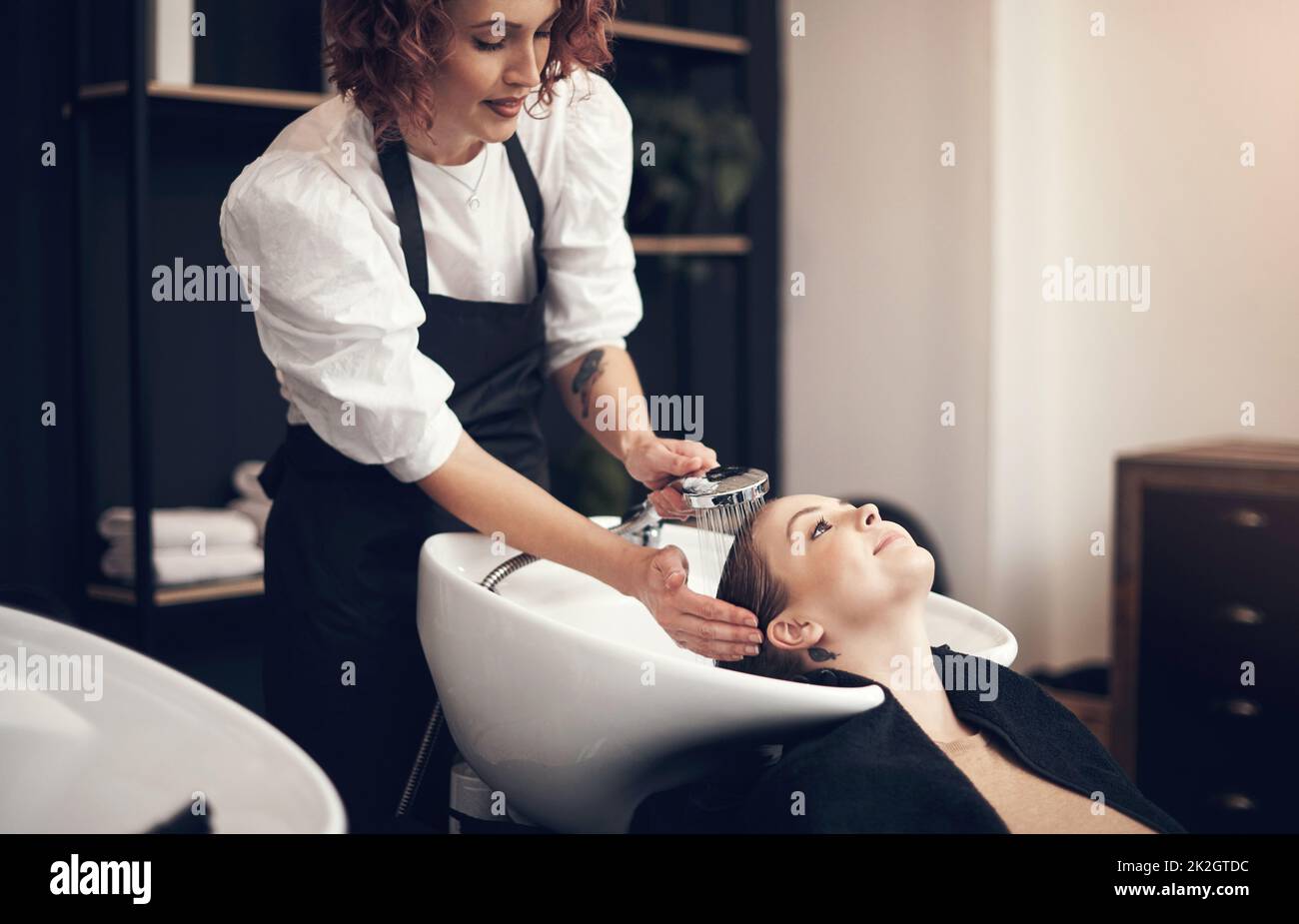 Achten Sie darauf, dass die Reinigung von der Wurzel bis zu den Spitzen durchgeführt wird. Aufnahme einer schönen jungen Frau, die im Salon ihre Haare waschen ließ. Stockfoto