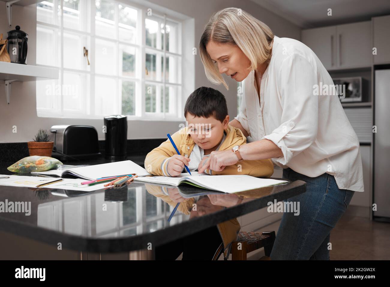 Wenn Sie es aufbrechen, ist es einfacher. Aufnahme einer schönen Mutter, die ihrem Sohn bei seinen Hausaufgaben hilft. Stockfoto