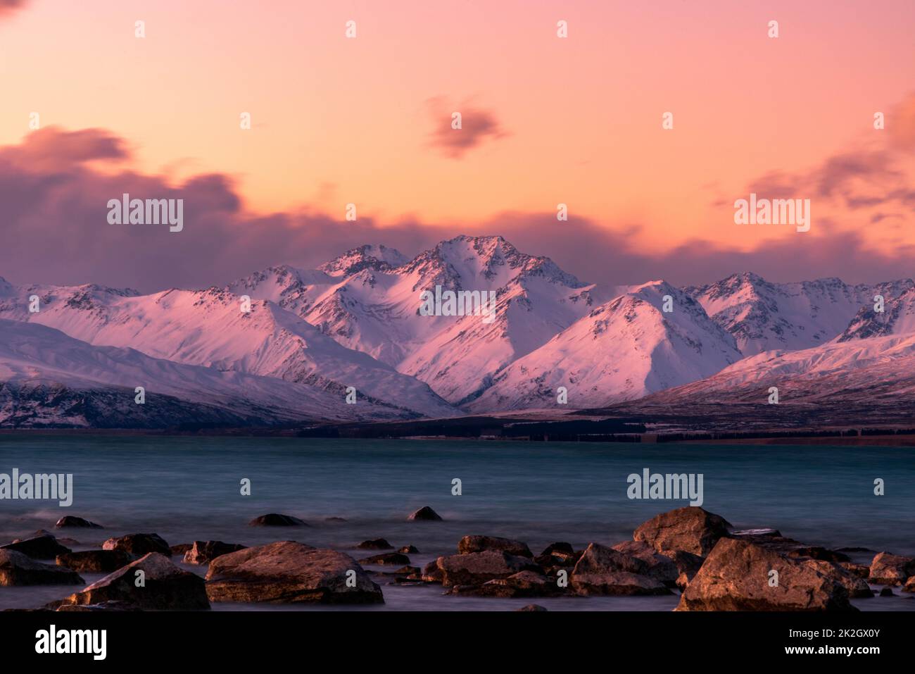 Das türkisfarbene Wasser des Lake Tekapo ist kurz nach Sonnenuntergang zu sehen. In der Ferne befindet sich das Mount Cook Gebirge in den Südlichen Alpen NZ. Stockfoto