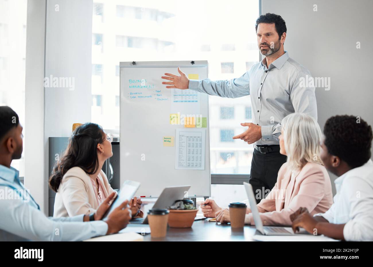 Du kannst immer besser sein als gestern. Foto eines gut aussehenden, reifen Geschäftsmanns, der während eines Meetings mit seinen Kollegen im Büro steht und eine Präsentation moderiert. Stockfoto