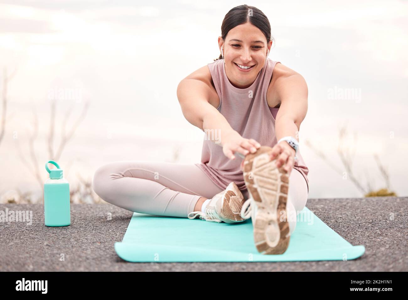 Nicht vergessen, sich zu strecken. Aufnahme einer jungen Sportlerin, die sich vor einem Lauf in der Natur dehnt. Stockfoto