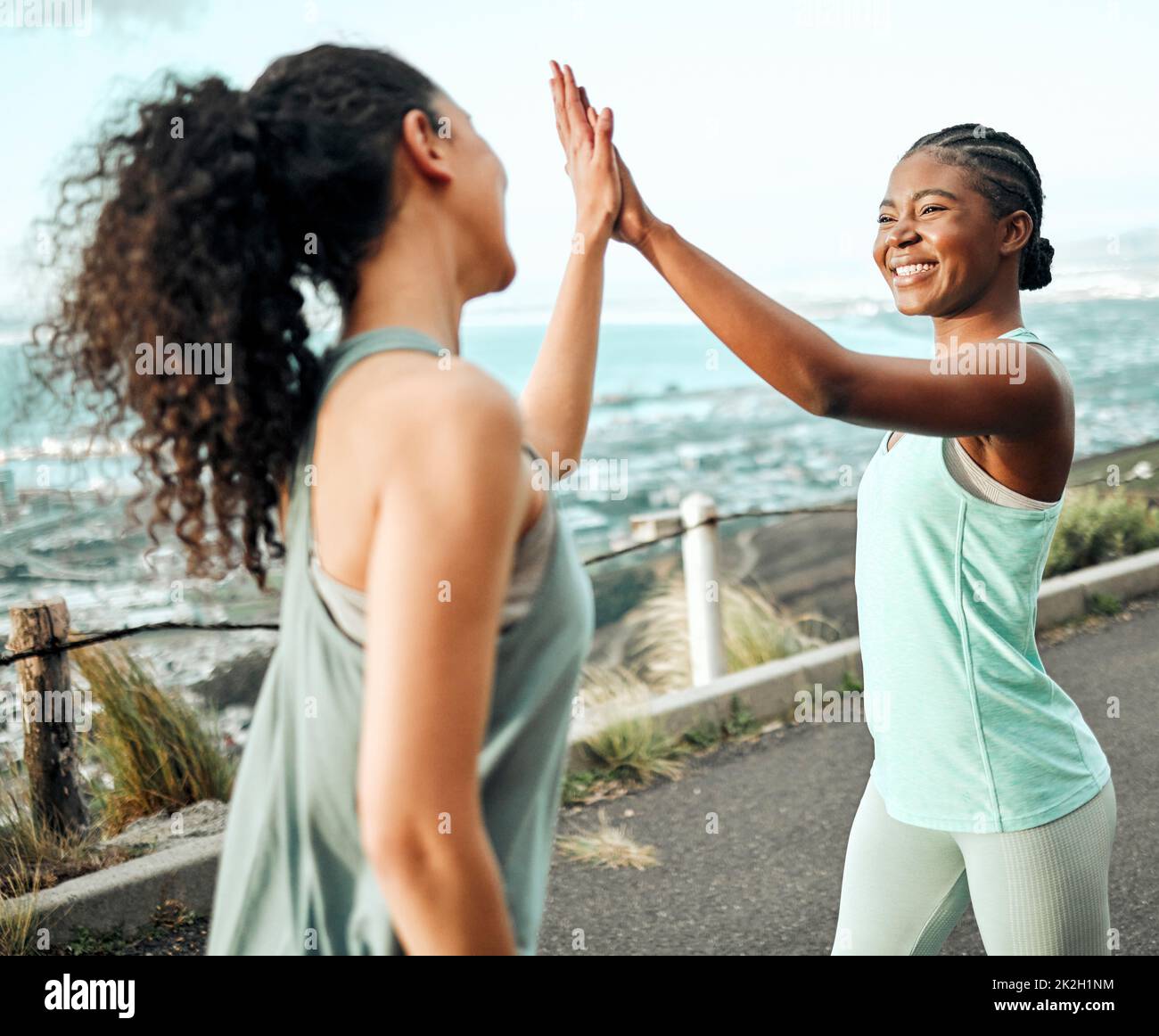 Wir haben ein weiteres Fitnessziel erreicht. Aufnahme von zwei jungen Frauen, die sich beim Ausarbeiten in der Natur eine hohe fünf gaben. Stockfoto