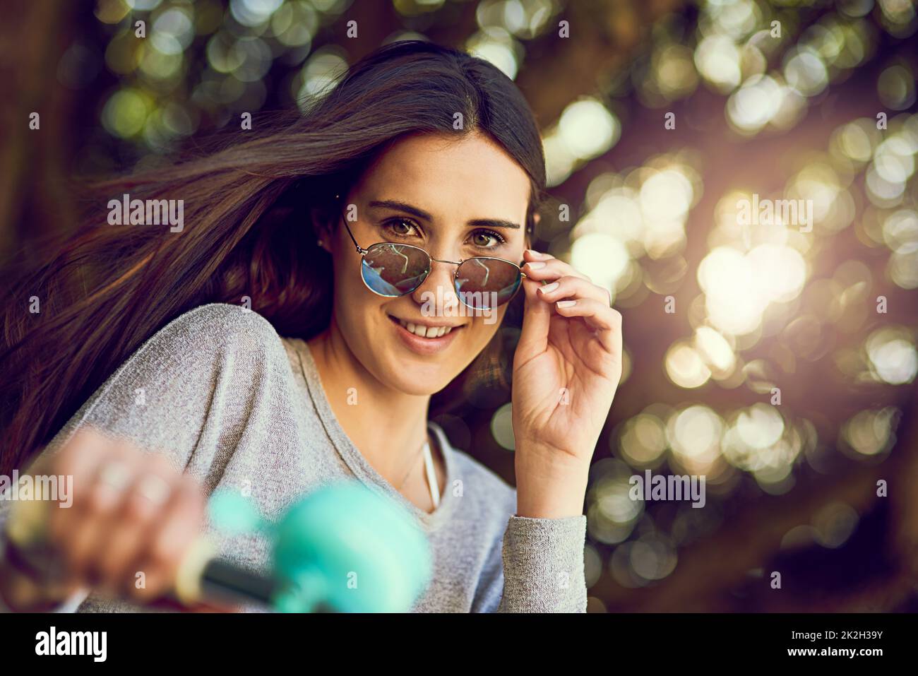 Hallo Sonnenschein. Porträt einer attraktiven jungen Frau, die draußen mit dem Fahrrad unterwegs ist. Stockfoto