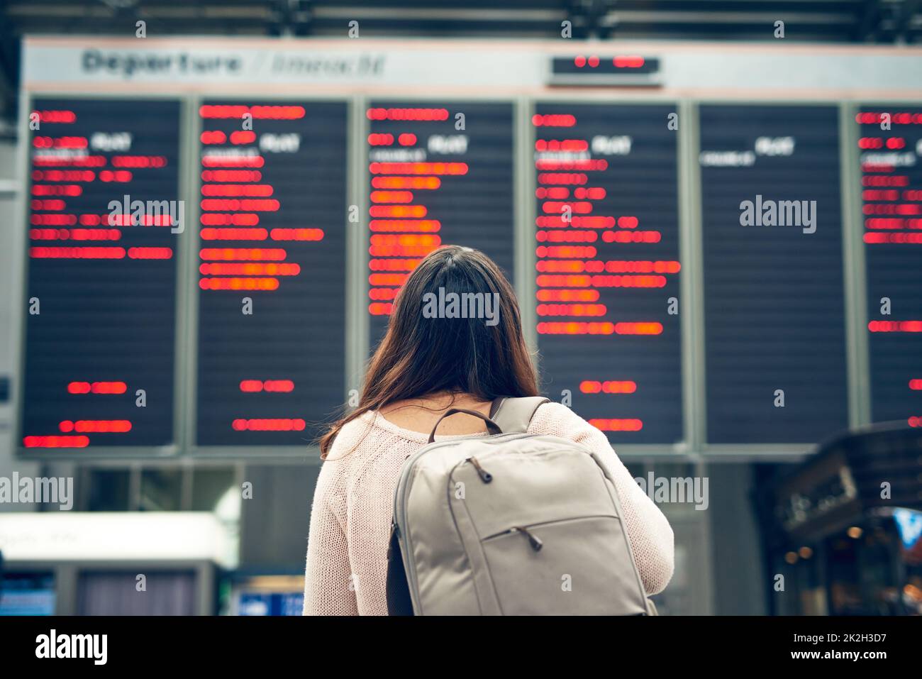 Lasst die Reise beginnen. Rückansicht einer nicht erkennbaren jungen Frau, die auf ein Ankunfts- und Abflugsbrett schaut, während sie auf einem Flughafen steht. Stockfoto
