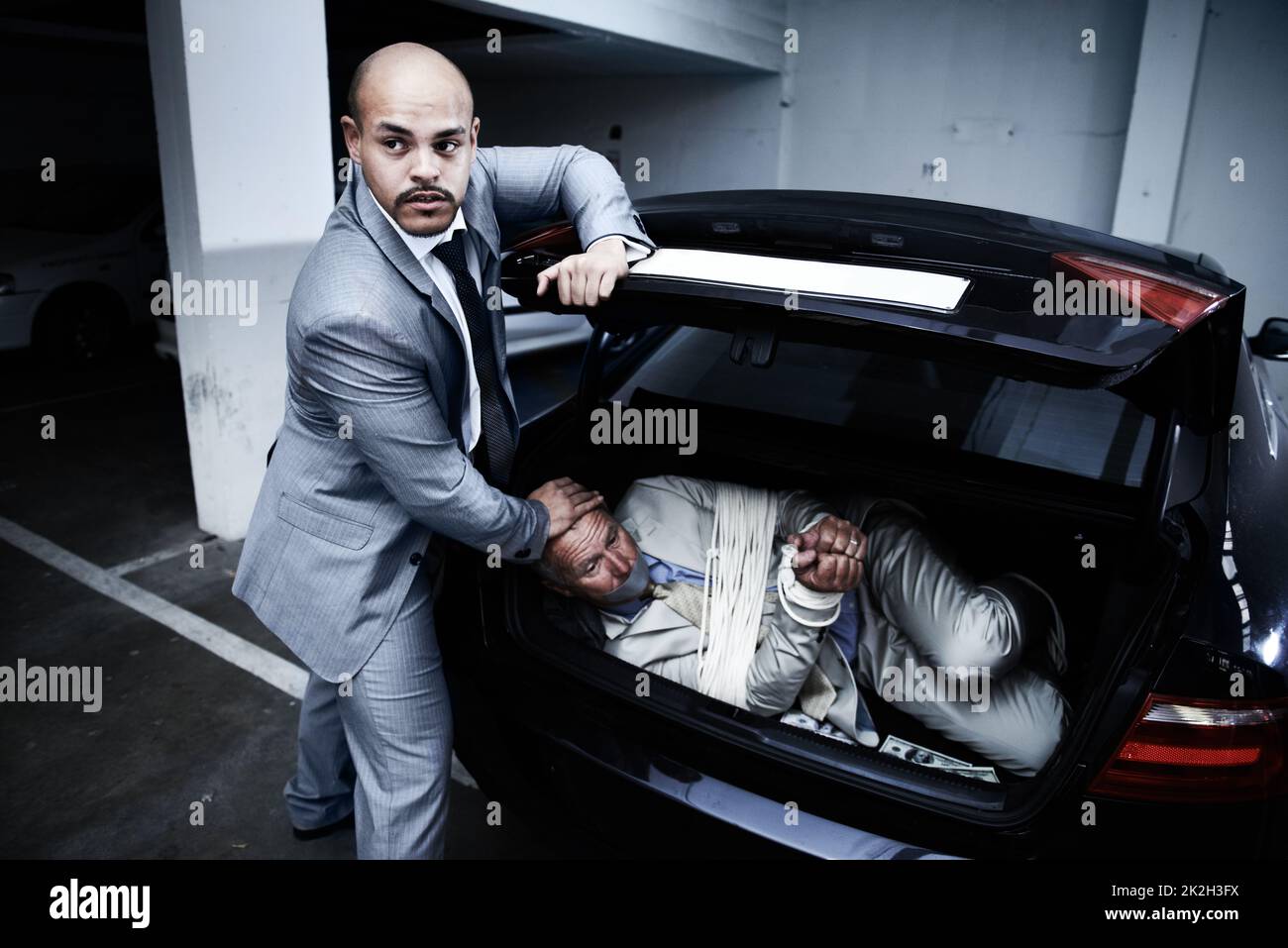 Gefangen vor Kriminellen. Ein Gangster stopfte einen gefesselten und geknebelten Geschäftsmann in den Kofferraum seines Autos. Stockfoto