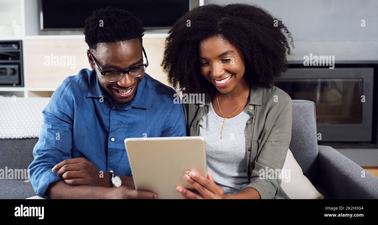Sehen Sie sich an, was online im Trend liegt. Aufnahme eines fröhlichen jungen Paares, das zu Hause ein digitales Tablet benutzt. Stockfoto