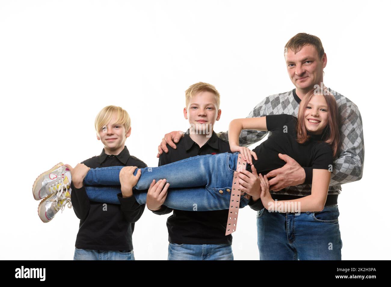 Vater und zwei Söhne, die ein Teenager-Mädchen in den Armen halten, tragen lässige Kleidung in dunklen Farben, weißer Hintergrund Stockfoto