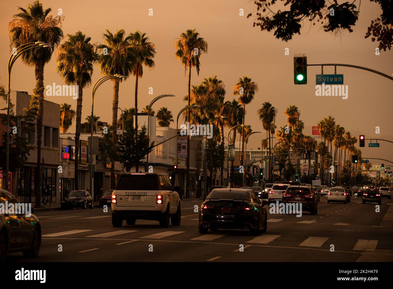 Van Nuys, Kalifornien, USA - 11. September 2022: Sonnenuntergang beleuchtet Palmen und Verkehr entlang des Van Nuys Blvd im Herzen der Innenstadt. Stockfoto