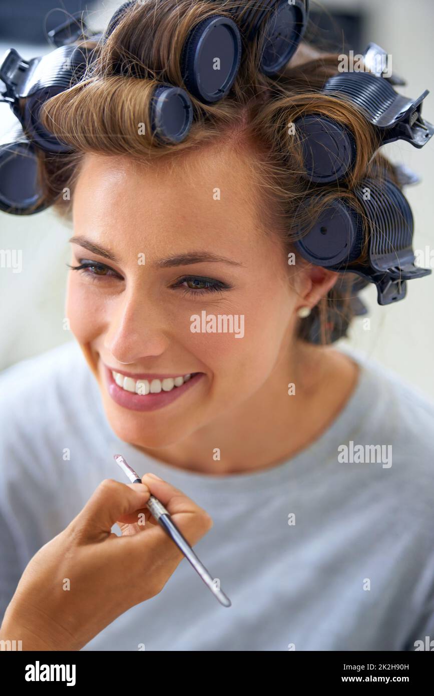 Lockig und sorglos. Eine schöne junge Frau, die den Tag damit verbringt, ihre Haare und ihr Make-up zu machen. Stockfoto