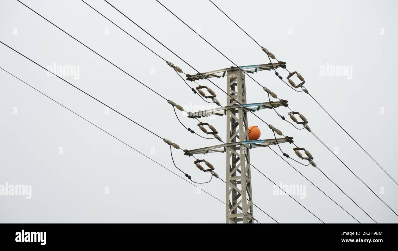 Nahaufnahme des oberen Teils eines Stromverteilungspylons und von Stromleitungen in niedriger Perspektive Stockfoto