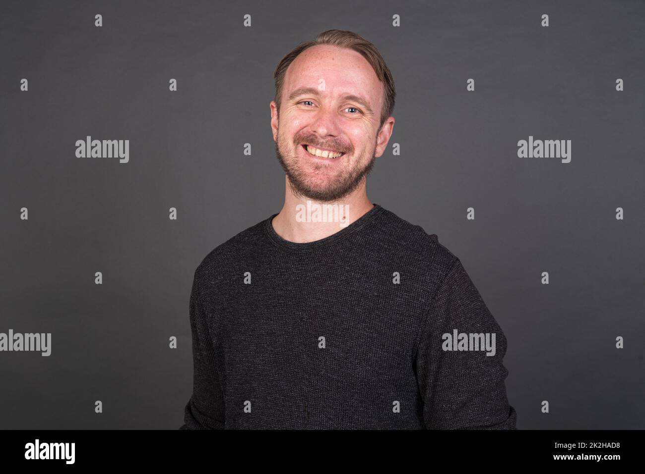 Studio-Porträt des blonden kaukasischen Mannes mit grauem Hemd Stockfoto