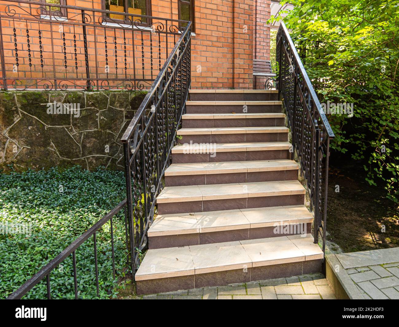 Eine schöne Treppe mit Metallgeländern erhebt sich zu einem roten Backsteingebäude Stockfoto