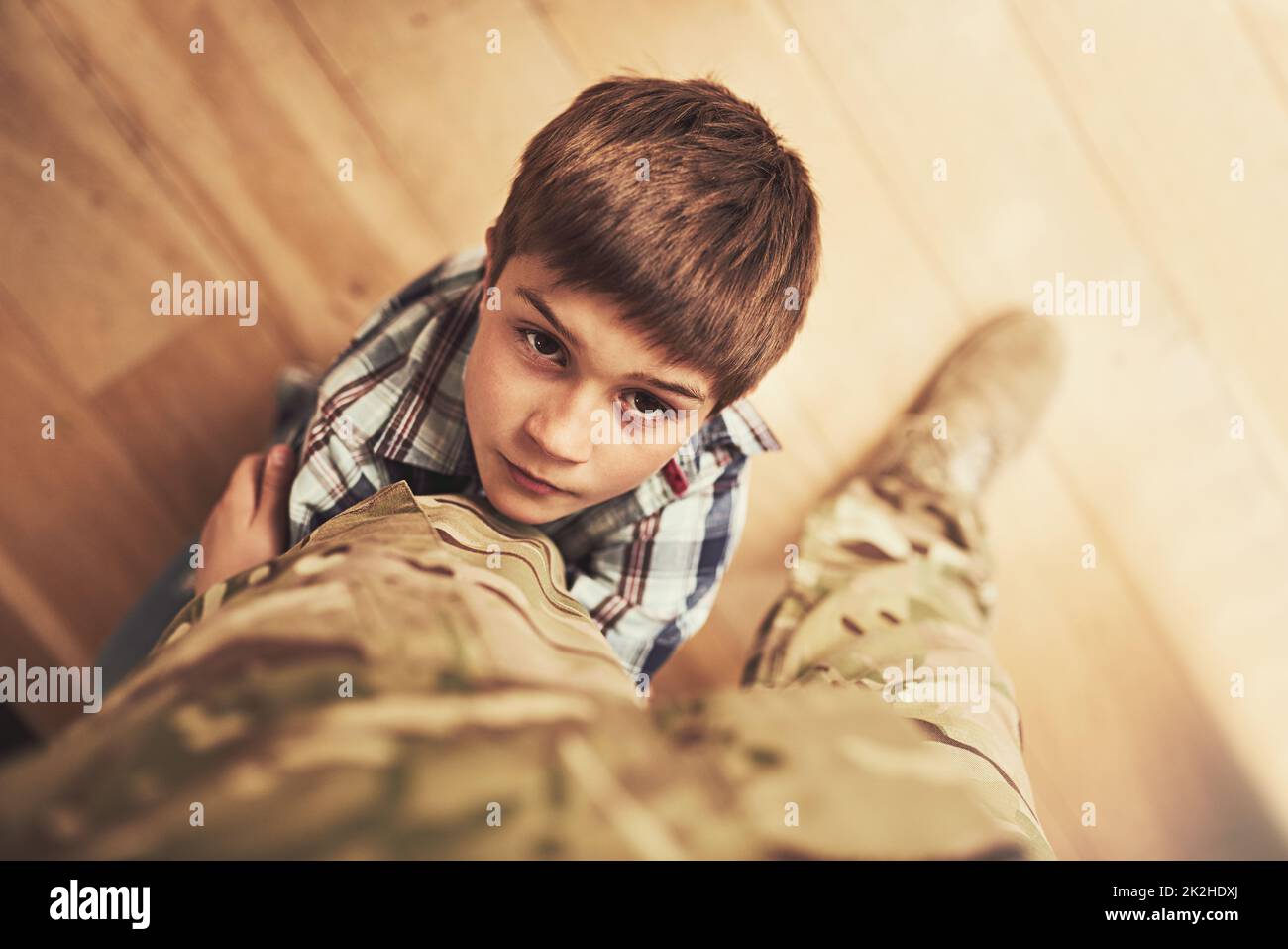 Müssen Sie wirklich gehen. Aufnahme eines Jungen, der sich an das Bein seines Vaters klammert, um ihn davon abzuhalten, zur Armee zu gehen. Stockfoto