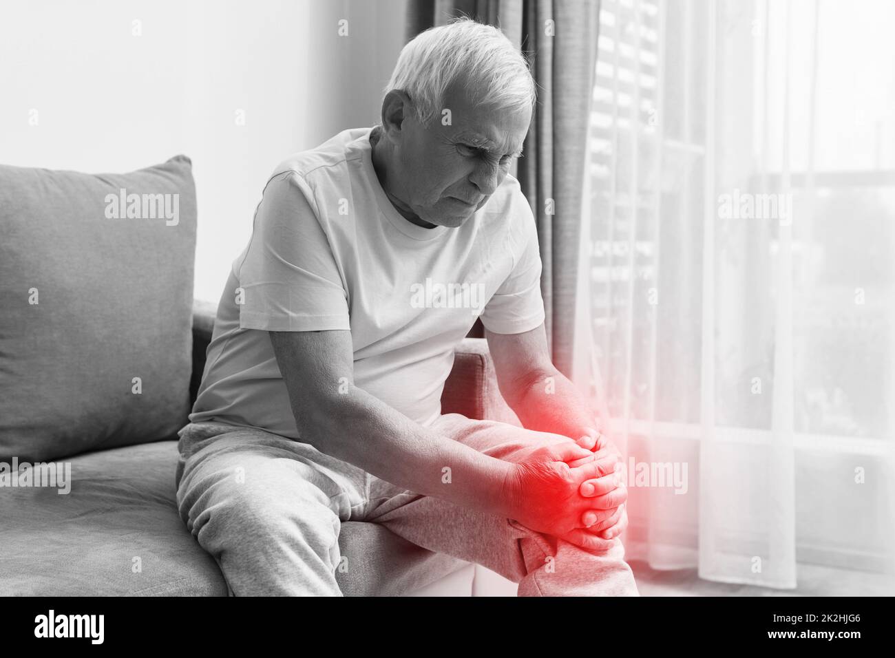 Seniorenmensch mit Knieschmerzen zu Hause. Stockfoto
