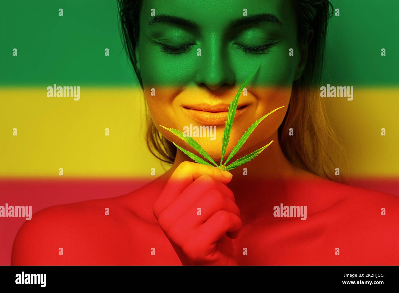 Portrait schöne Frau mit einem Cannabisblatt in den Farben der rastafarischen Flagge Stockfoto