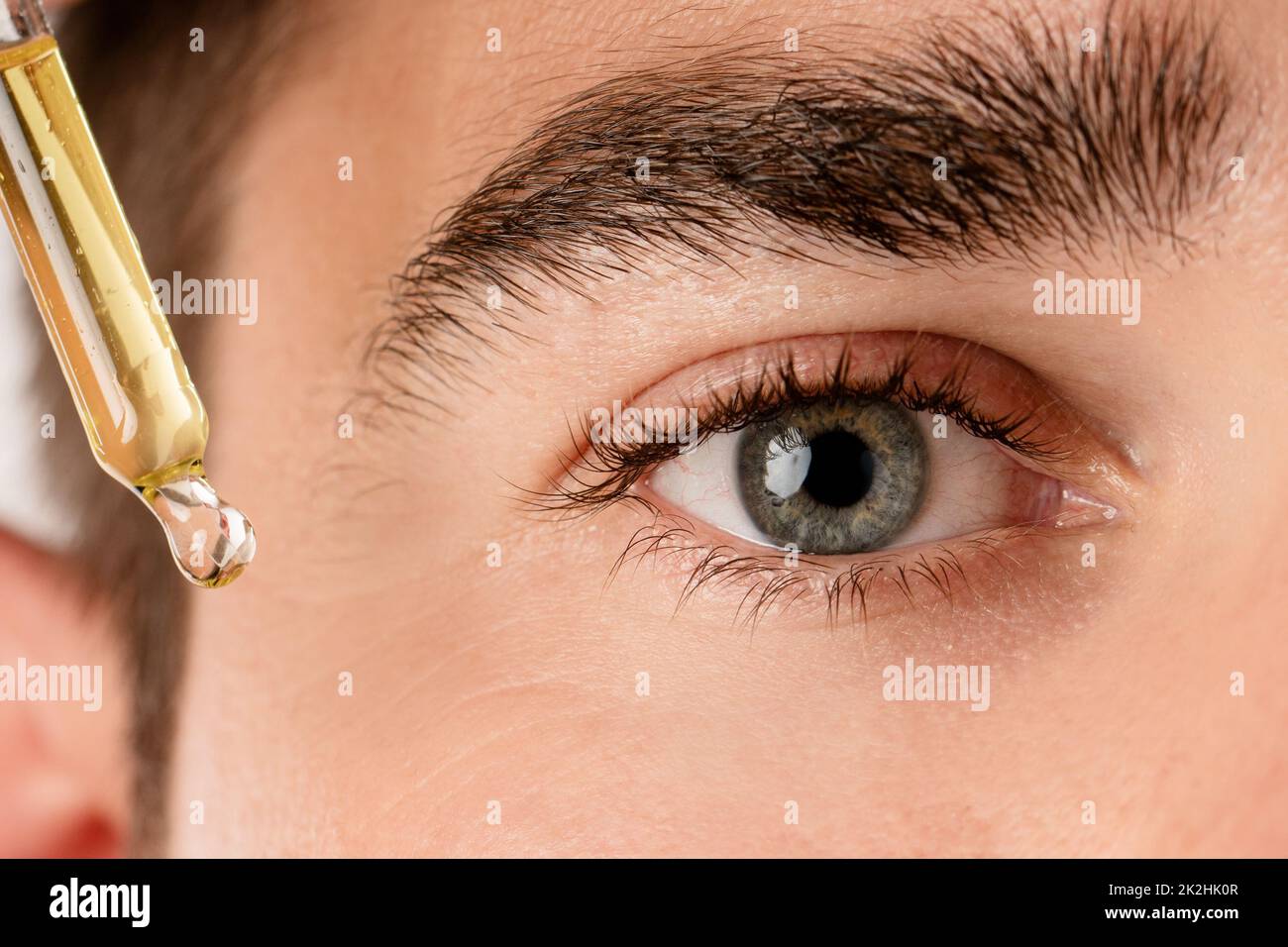 Männliches Auge und Pipette mit einem feuchtigkeitsspendenden Öl Stockfoto